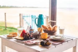 a table with breakfast foods and glasses of milk at Pousada Luar das Águas in Ilha de Boipeba