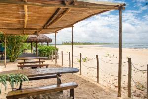 dos mesas de picnic y bancos en la playa en Pousada Luar das Águas, en Isla de Boipeba