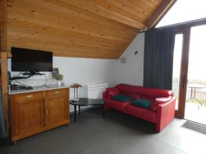 een woonkamer met een rode bank en een flatscreen-tv bij Studio with More than a View in Maldegem