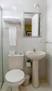 Baño blanco con aseo y lavamanos en Hotel Pousada do Sol en Ubatuba
