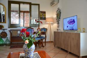 a living room with a tv and a vase with flowers on a table at Exlusive Pool Villa - Cascina Relais in Comiso