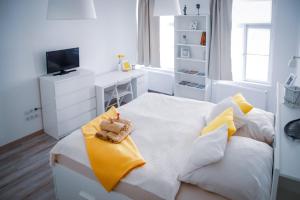 - une chambre blanche dotée d'un lit avec un ours en peluche dans l'établissement Malasits Art Home, à Győr