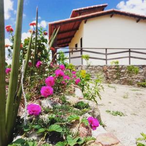 un jardín con flores rosas frente a una casa en Chalé bons ventos en Serra de São Bento