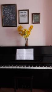 a black piano with a vase of yellow flowers on it at Hostel Khanh Hương 2 in Da Lat