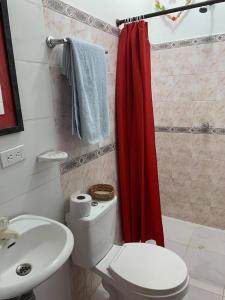 La salle de bains est pourvue de toilettes et d'un rideau de douche rouge. dans l'établissement Apartamentos y Estudios Manga Real, à Carthagène des Indes