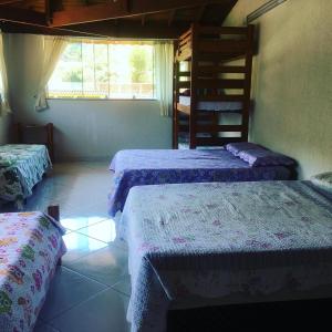 1 dormitorio con 3 camas y ventana en Takeo's House, en Boicucanga