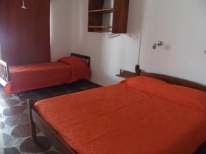 2 Betten in einem Zimmer mit orangefarbener Bettwäsche in der Unterkunft Hotel Buena Vista Se reserva solo con seña in San Gregorio de Polanco
