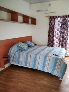 1 dormitorio con 1 cama con cabecero de madera y ventana en La Comarca en Colonia del Sacramento