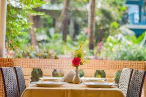 a table with a vase with a red flower on it at Hotel Siesta De Goa in Varca