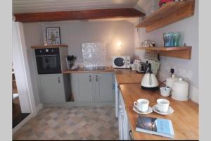 a kitchen with white cabinets and a wooden counter top at Charming original fishermans cottage on Dungeness beach in Dungeness +31 photos