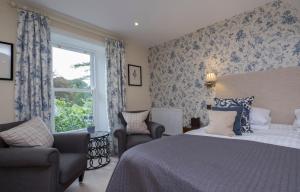 a bedroom with a bed and two chairs and a window at The Grasmere Hotel in Grasmere