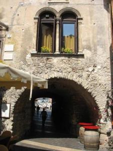 a person walking through a tunnel under a building with a window at Palazzo Fregoso in Garda
