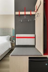 a small bedroom with a bed and a refrigerator at avid hotels - Boston Logan Airport - Revere, an IHG Hotel in Revere