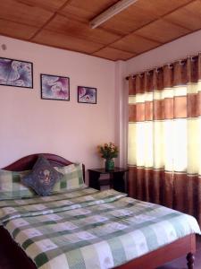 大叻的住宿－Hostel Khanh Hương 2，一间卧室配有床和两个带窗帘的窗户