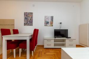 um quarto com uma mesa e cadeiras vermelhas e uma televisão em Apartman Nađa em Zlatibor
