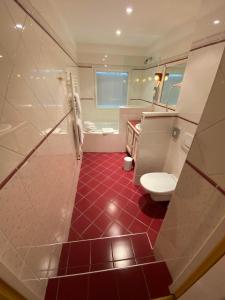 a bathroom with a red tile floor and a toilet at Best Western La Metairie in Gosnay