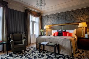 um quarto de hotel com uma cama e uma cadeira em Grandhotel Pupp em Karlovy Vary