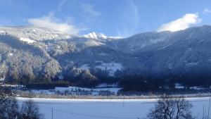 a snowy mountain range with a lake in the foreground at Ferienwohnungen Rosi in Kleblach