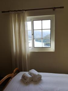 a bedroom with a window and two towels on a bed at Casa de Bouças in São Pedro