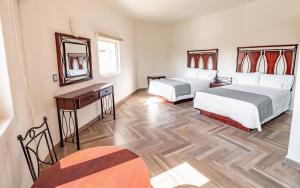 una camera d'albergo con due letti e uno specchio di Hotel Alcazar - Guadalajara Centro Historico a Guadalajara