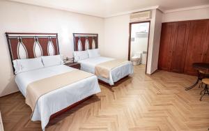 una camera d'albergo con due letti e un tavolo di Hotel Alcazar - Guadalajara Centro Historico a Guadalajara