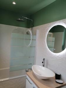 een badkamer met een witte wastafel en een spiegel bij Maison avec garage, terrasse, l'Herboristerie in Béthune