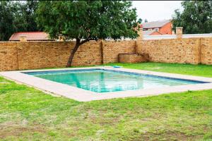 a swimming pool in a yard next to a brick wall at The Wilcrest Apartment in Randjesfontein