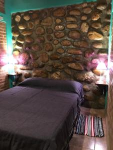 a stone wall with a bed in a bedroom at Departamentos la Familia NONO in Nono