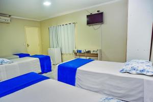 a room with three beds and a tv on the wall at Exclusive Hotel in Petrolina