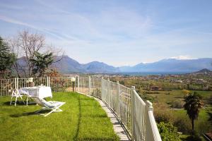 a white chair and table on a balcony with mountains at La Villa Degli Ulivi in Soiano del Lago