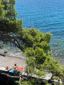 Un paio di persone sedute su una spiaggia vicino all'acqua di RIA Lungomare a Fiume (Rijeka)