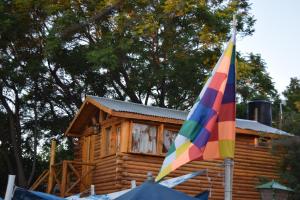 a colorful umbrella in front of a log cabin at Infinito Chill0ut in San Marcos Sierras