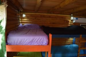 a bed in a wooden cabin with purple sheets at Infinito Chill0ut in San Marcos Sierras