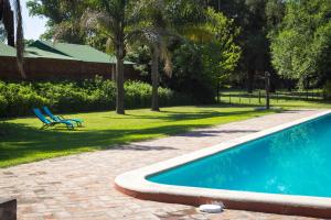 una piscina con 2 sillas azules en un patio en Estancia La Cinacina en San Antonio de Areco