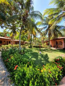 a garden with palm trees and flowers in front of a building at Pousada do Riacho in Barreirinhas