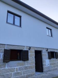 a white building with three windows and a door at Casa da Viela in Arouca