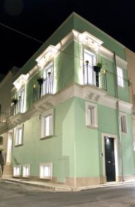 un bâtiment vert avec 2 balcons dans une rue dans l'établissement Domus Le Ceramiche, à Grottaglie