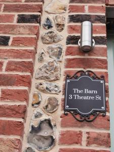 a sign on the side of a brick wall with rocks at The Barn in Swaffham