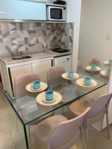 a kitchen with a glass table and chairs with cups and saucers at Manawa Flat A14 in Porto De Galinhas