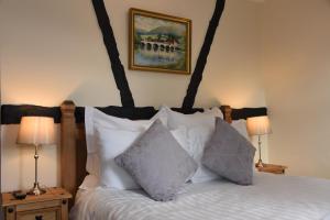 1 dormitorio con 1 cama con almohadas blancas en The Llanelwedd Arms Hotel, en Builth Wells