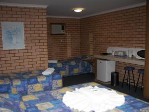 a room with two beds and a table and a kitchen at Bega Southtown Motor Inn in Bega