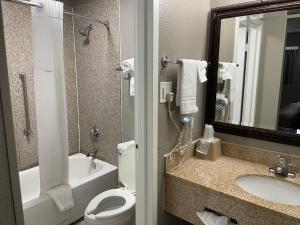 a bathroom with a toilet and a sink and a mirror at Days Inn & Suites by Wyndham Collierville Germantown Area in Collierville