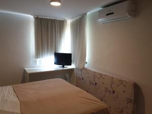 Un dormitorio con una cama y una ventana con un televisor. en Flat à beira mar em João Pessoa -Pacific Flat, en João Pessoa