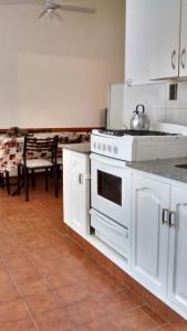 a kitchen with a white stove and a table at Cabañas San Gabriel Carlos Paz in Villa Carlos Paz