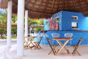 a table and chairs on a beach with a blue wall at Hotel Puerto Holbox Beach Front in Holbox Island