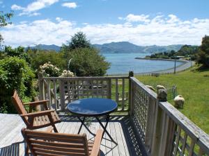 a deck with two chairs and a table and a dog at Roselle Farm Cottage in Portobello