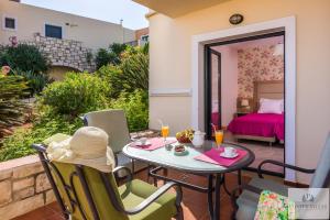 a patio with a table and chairs and a bed at Pilot's Villas Luxury Suites in Hersonissos