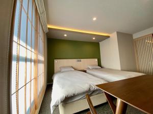 a bedroom with two beds and a table and a window at HIZ HOTEL Gion-Shirakawa in Kyoto
