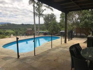 Byron Bay hinterland house - amazing sunset views! في Myocum: مسبح في فناء مع طاولة وكراسي