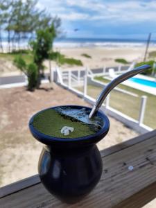 uma chávena preta com uma colher sentada numa mesa perto da praia em Casa de Praia - Frente para o MAR em Xangri-lá